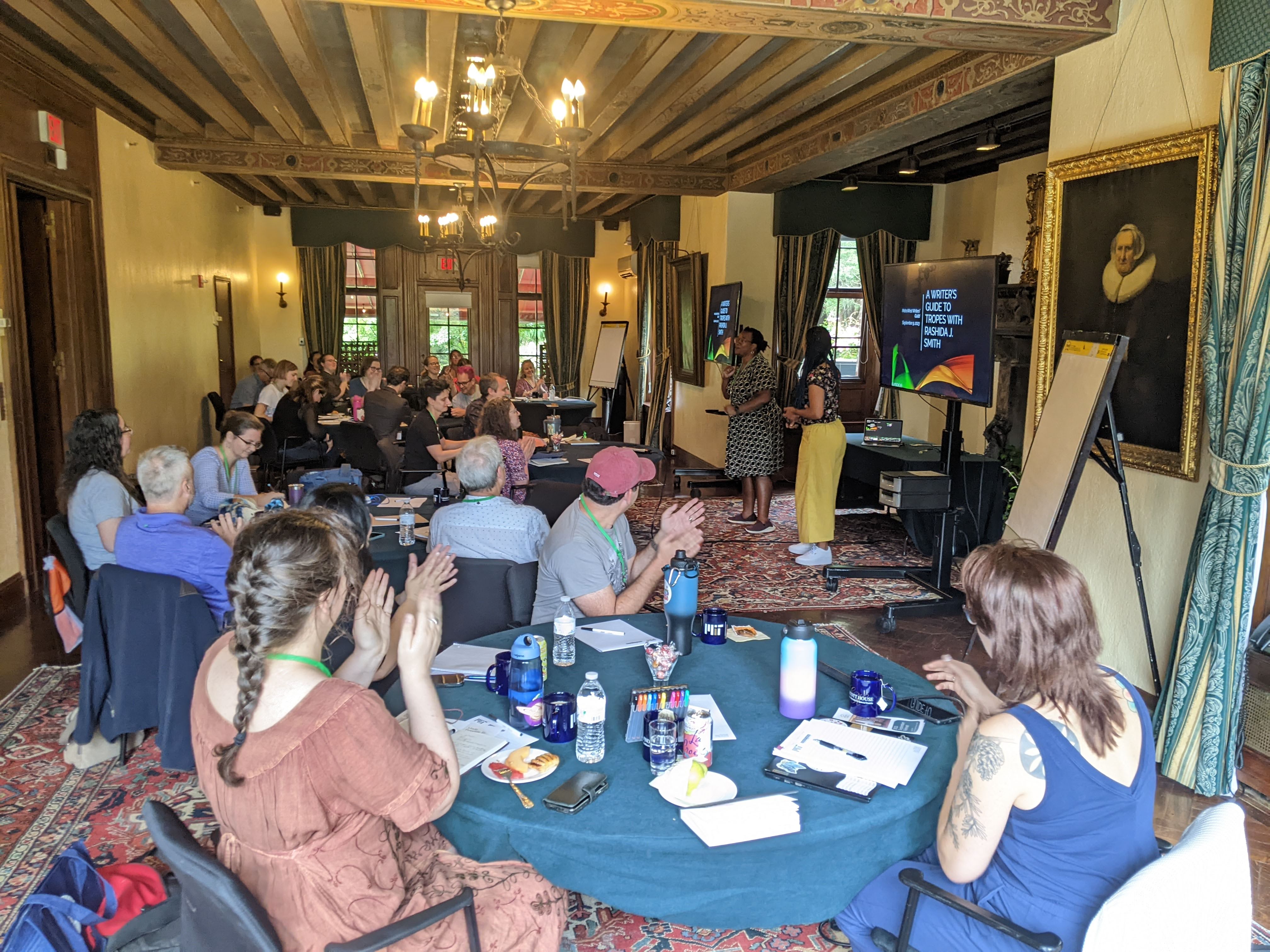 Members of the Metro West Writers Guild gathered around tables with their notebooks to watch a presentation on writing craft at one of our many in-person events